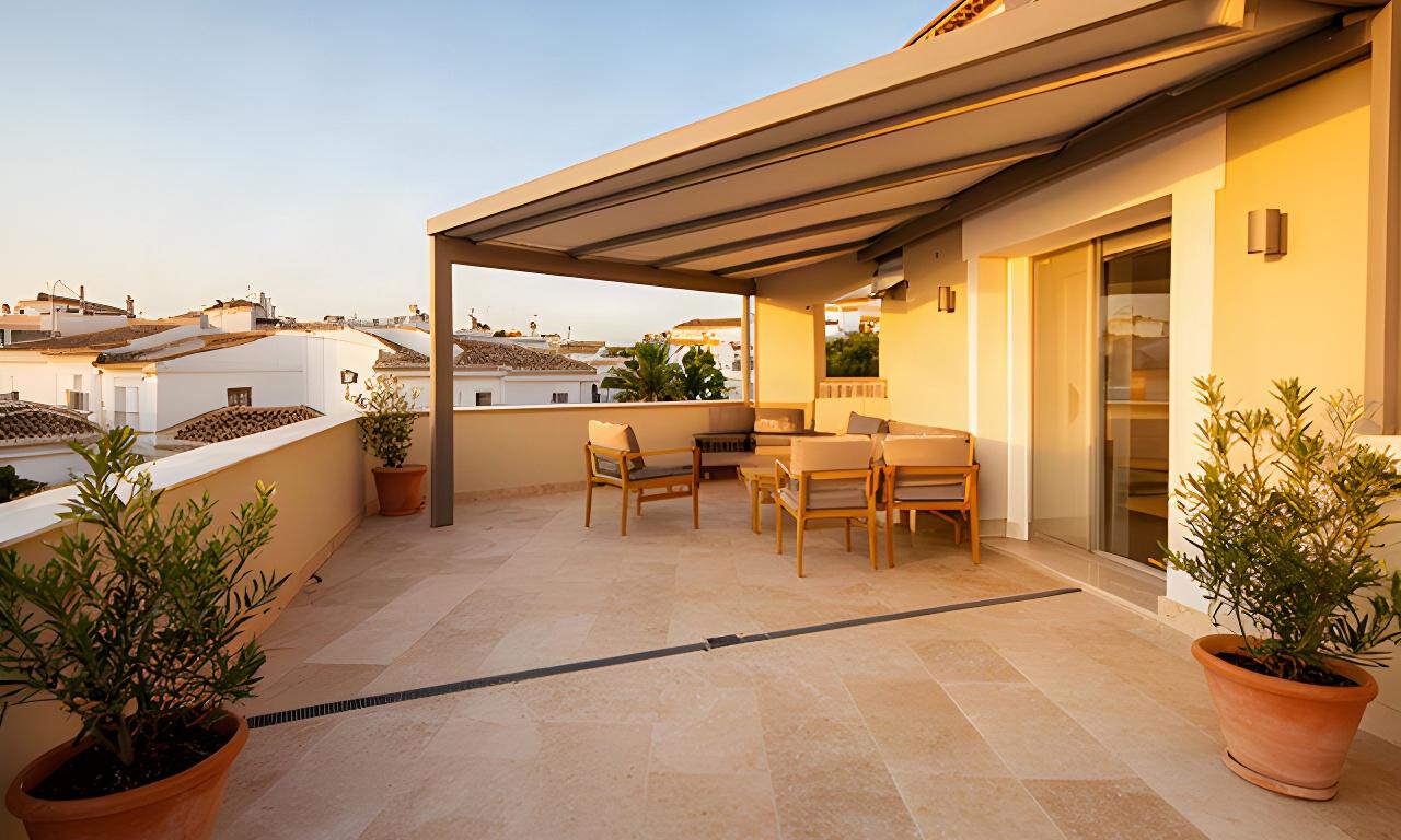 Terraza residencial renovada en Guillena con suelo de piedra, cubierta ligera y zona de descanso